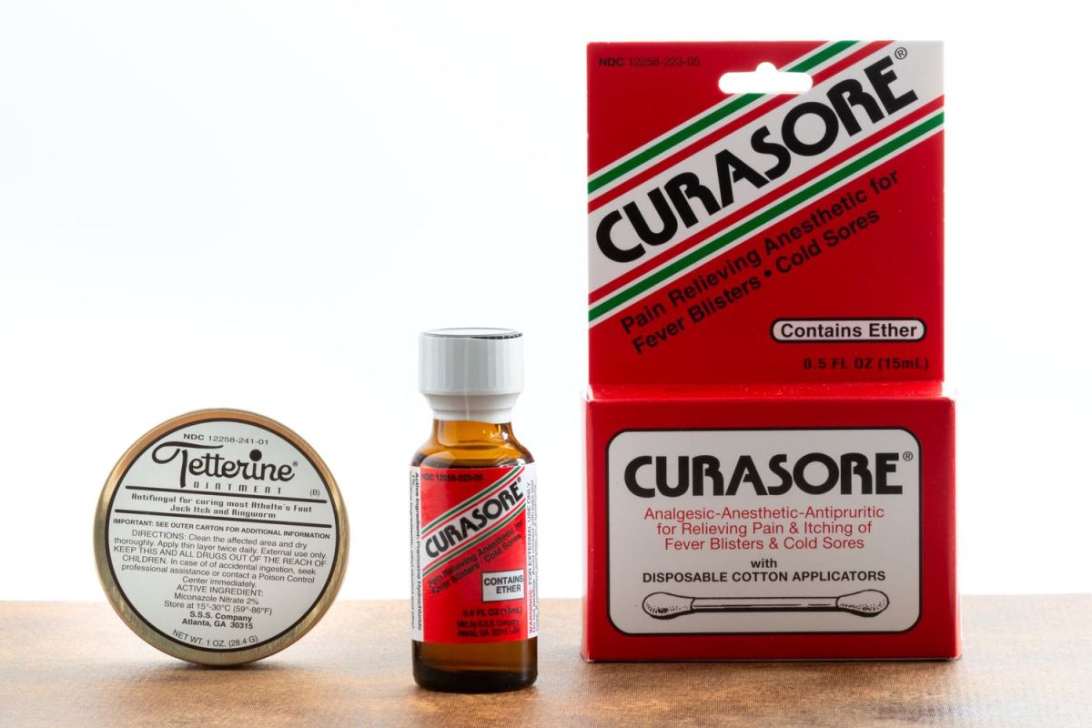 Tetterine Green tin, Curasore bottle, and Curasore box on a wooden surface